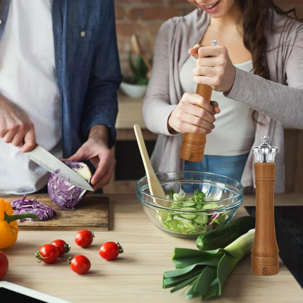 Two people preparing a salad with vegetables on a kitchen counter.