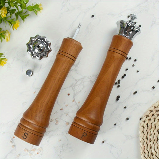 Wooden pepper and salt grinders on a light surface with scattered peppercorns.